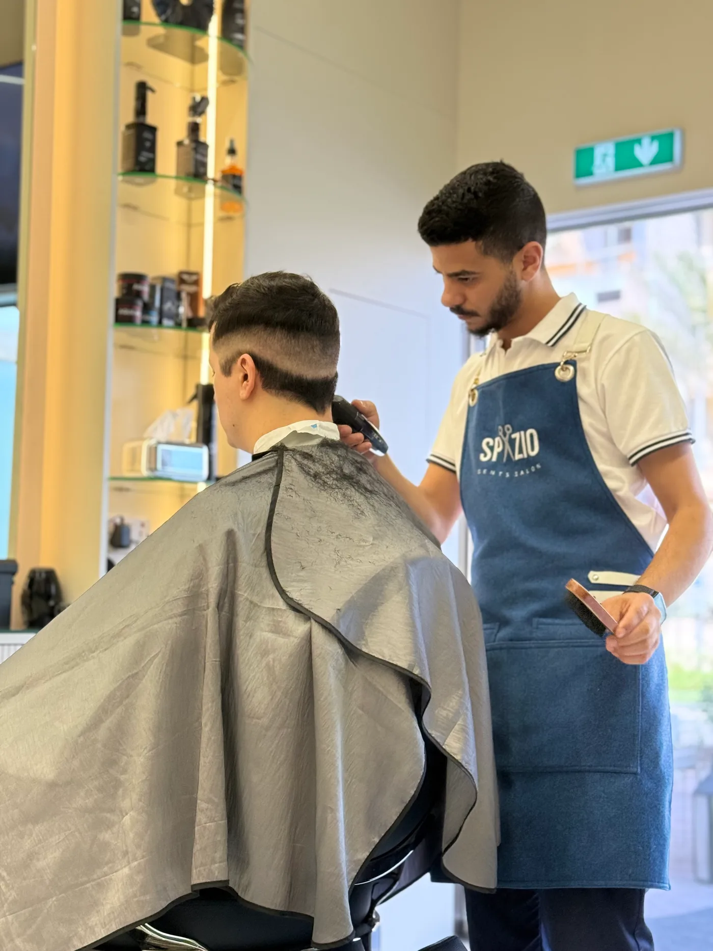 Barber in a Spazio apron working a clipper fade at Spazio Gents Salon in JVC, Dubai