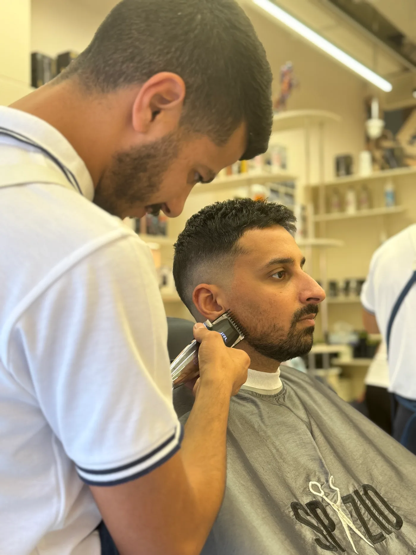Barber lining up a skin fade with clippers at Spazio Gents Salon JVC