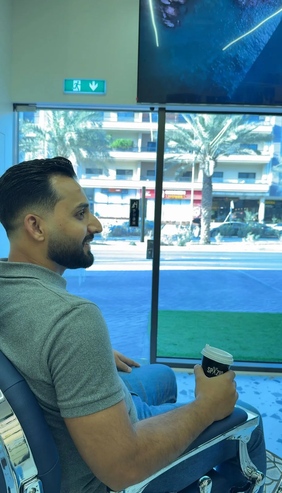 Client waiting by the window at Spazio Gents Salon in Jumeirah Village Circle