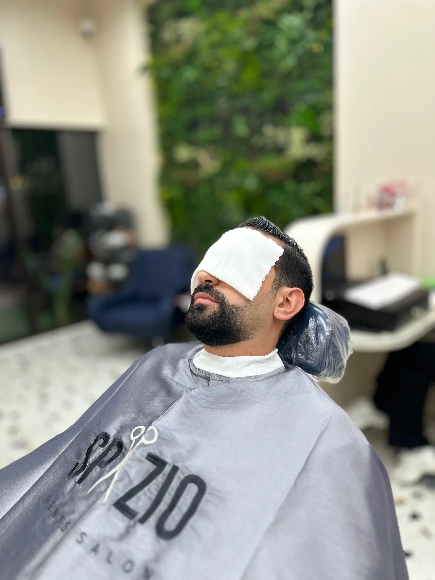 Men's facial treatment at Spazio Gents Salon in front of the green living wall, JVC