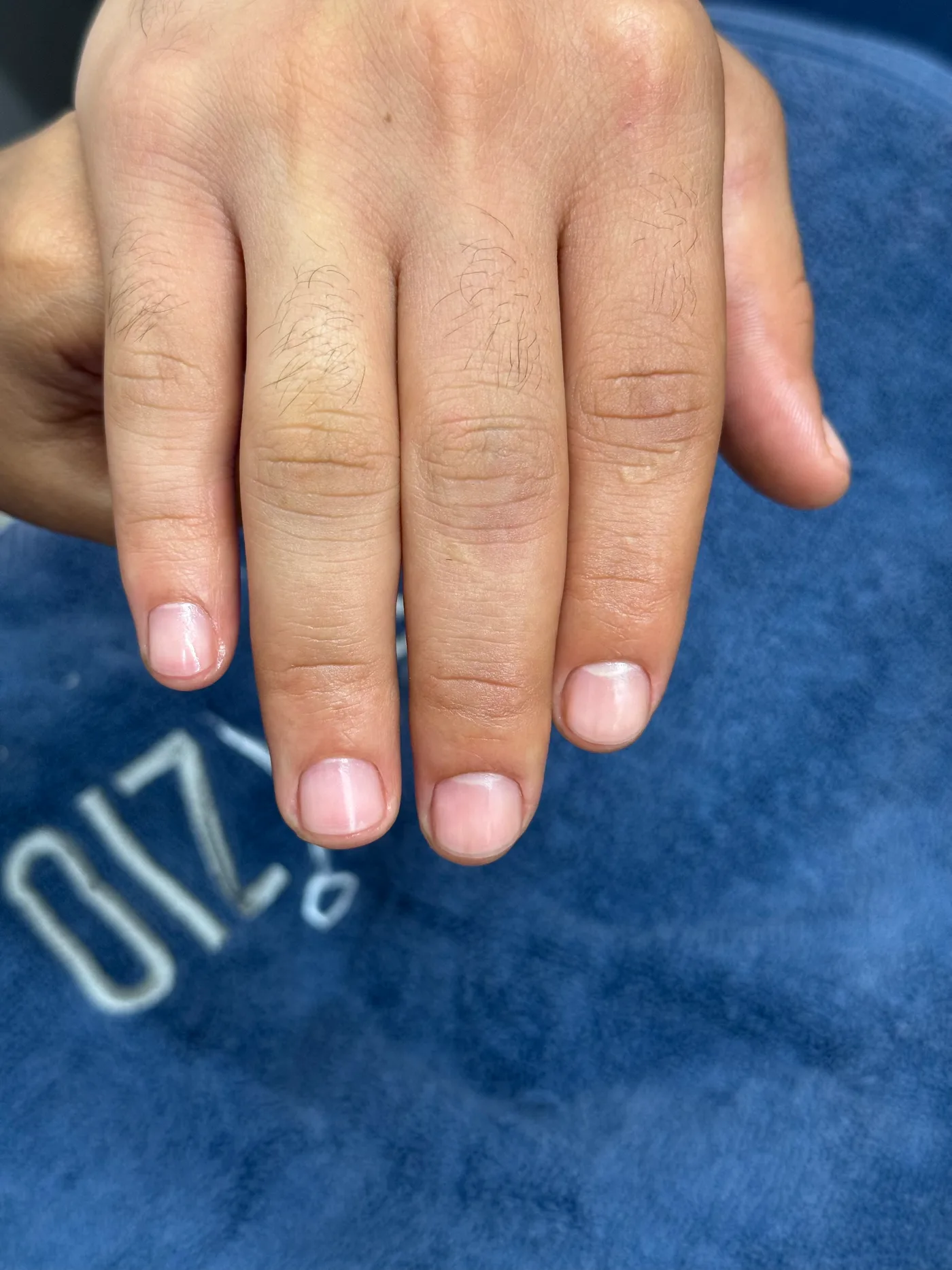 Finished men's manicure showing clean, shaped nails on a Spazio towel in JVC, Dubai