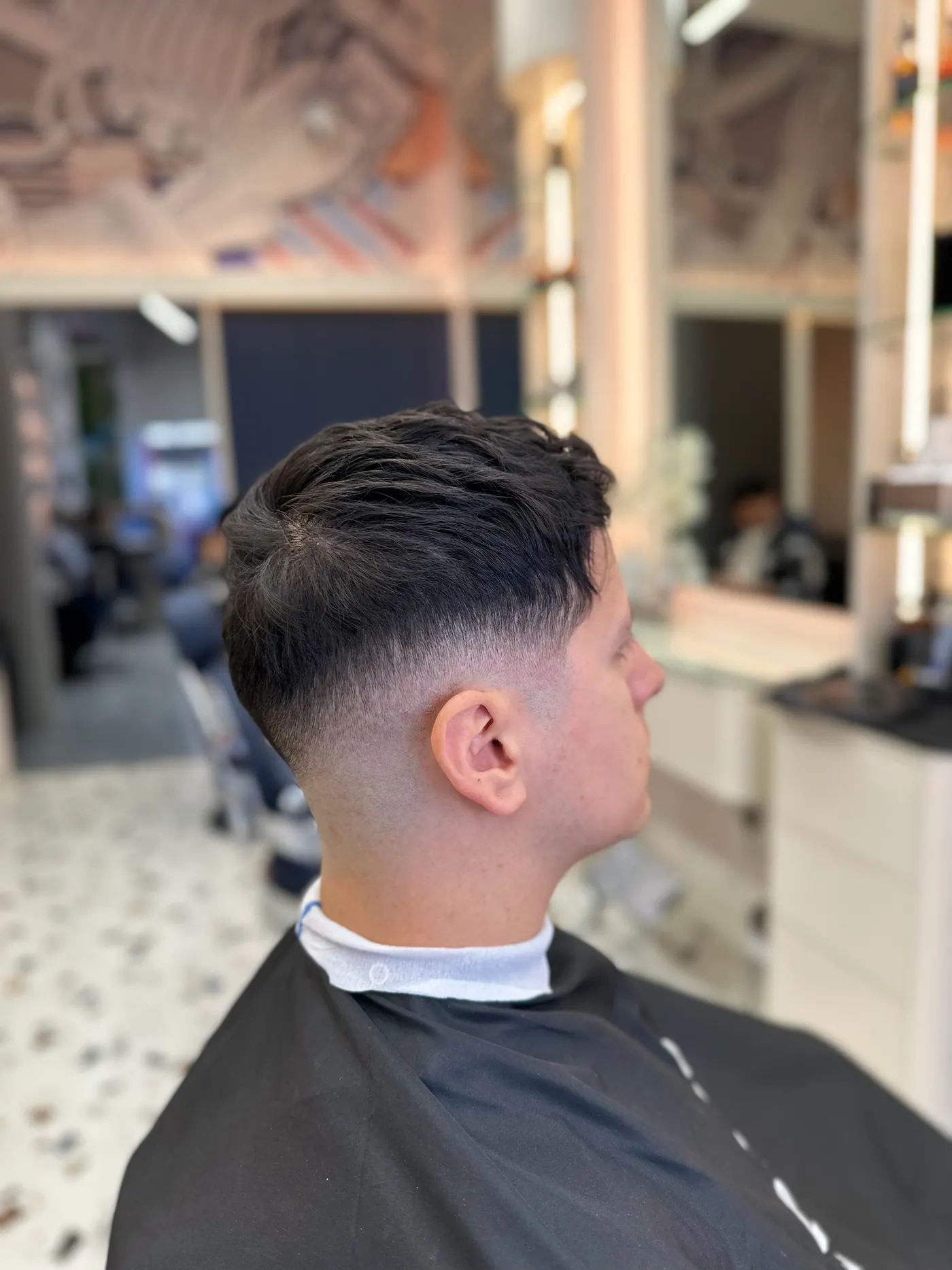 Side profile of a finished mid fade with a textured top, cut at Spazio Gents Salon in JVC