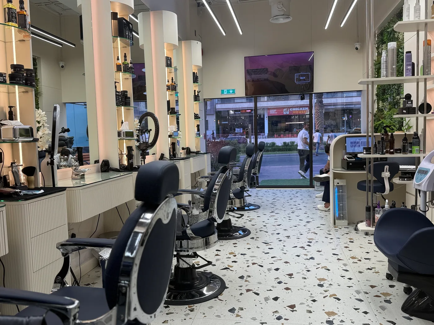 Barber chairs and street-facing window inside Spazio Gents Salon in JVC, Dubai, open until midnight