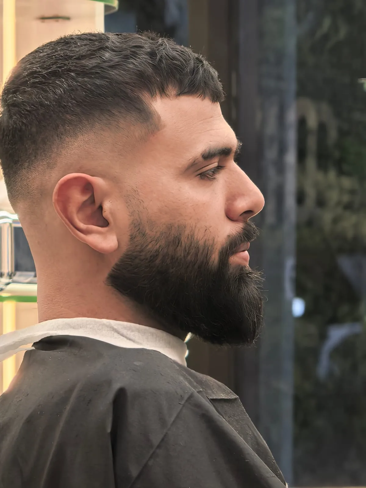 Side profile of a finished fade and shaped beard at Spazio Gents Salon in JVC