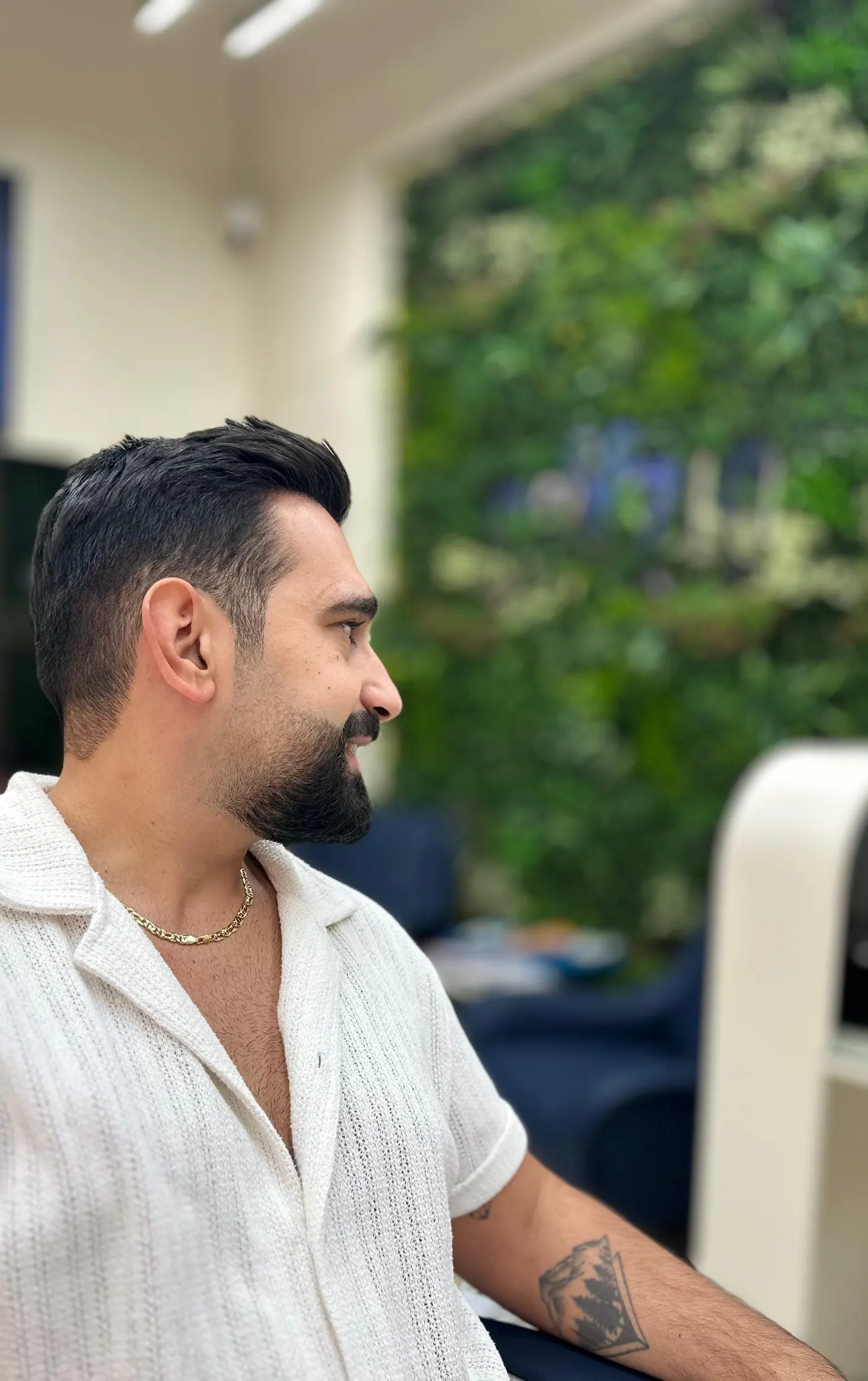 Client with a finished skin fade and shaped beard beside the green living wall at Spazio Gents Salon in JVC, Dubai
