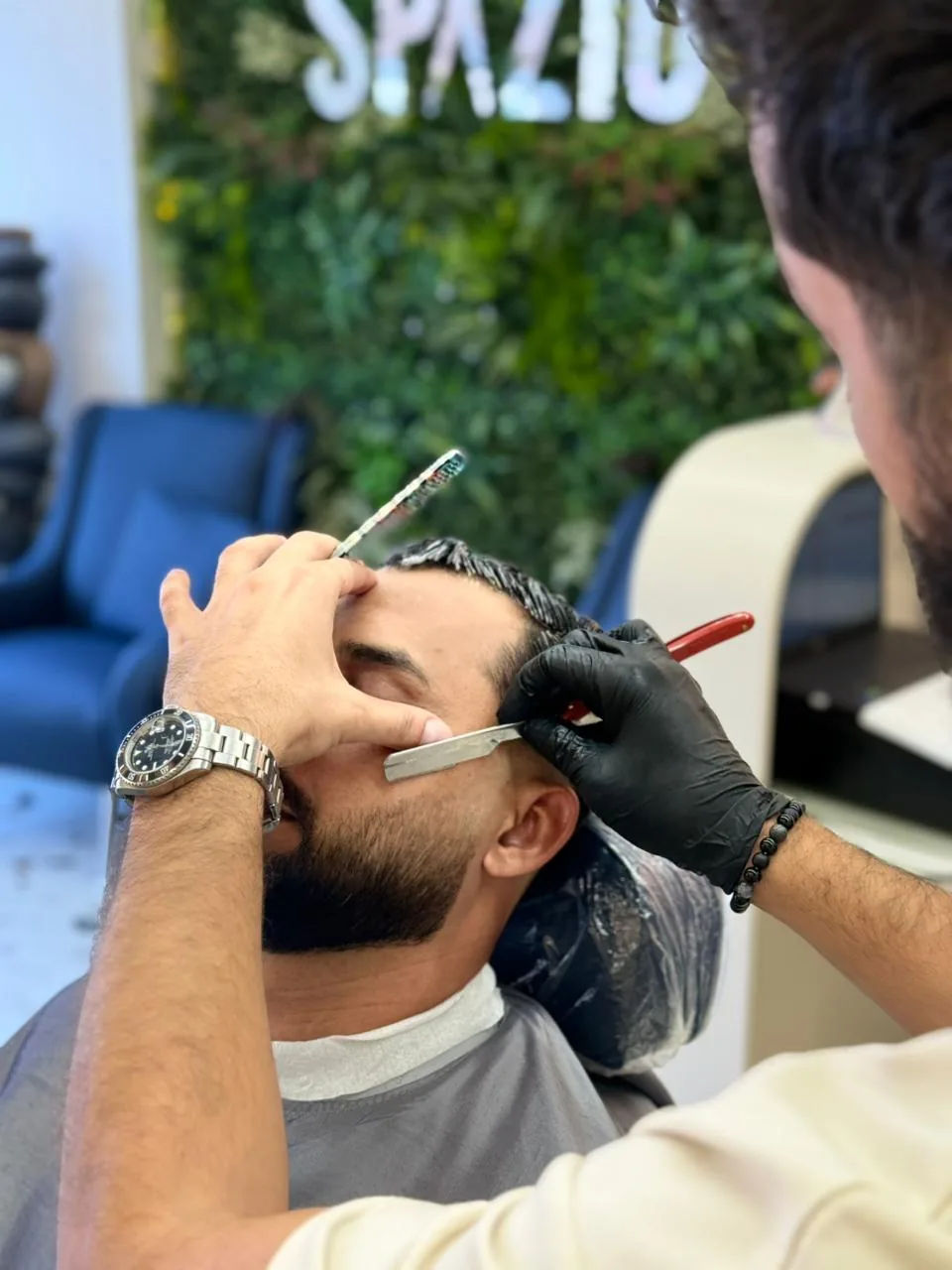 Barber using a straight razor to line up a client at Spazio Gents Salon in JVC, Dubai