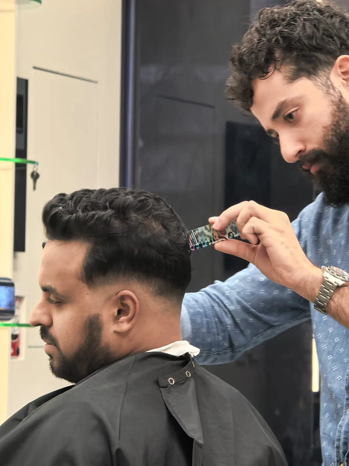 Barber shaving a client's neckline with a straight razor at Spazio Gents Salon in JVC