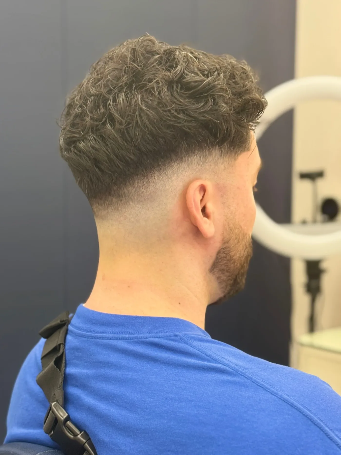 Back view of a curly top with a skin fade, finished haircut at Spazio Gents Salon in Jumeirah Village Circle, Dubai